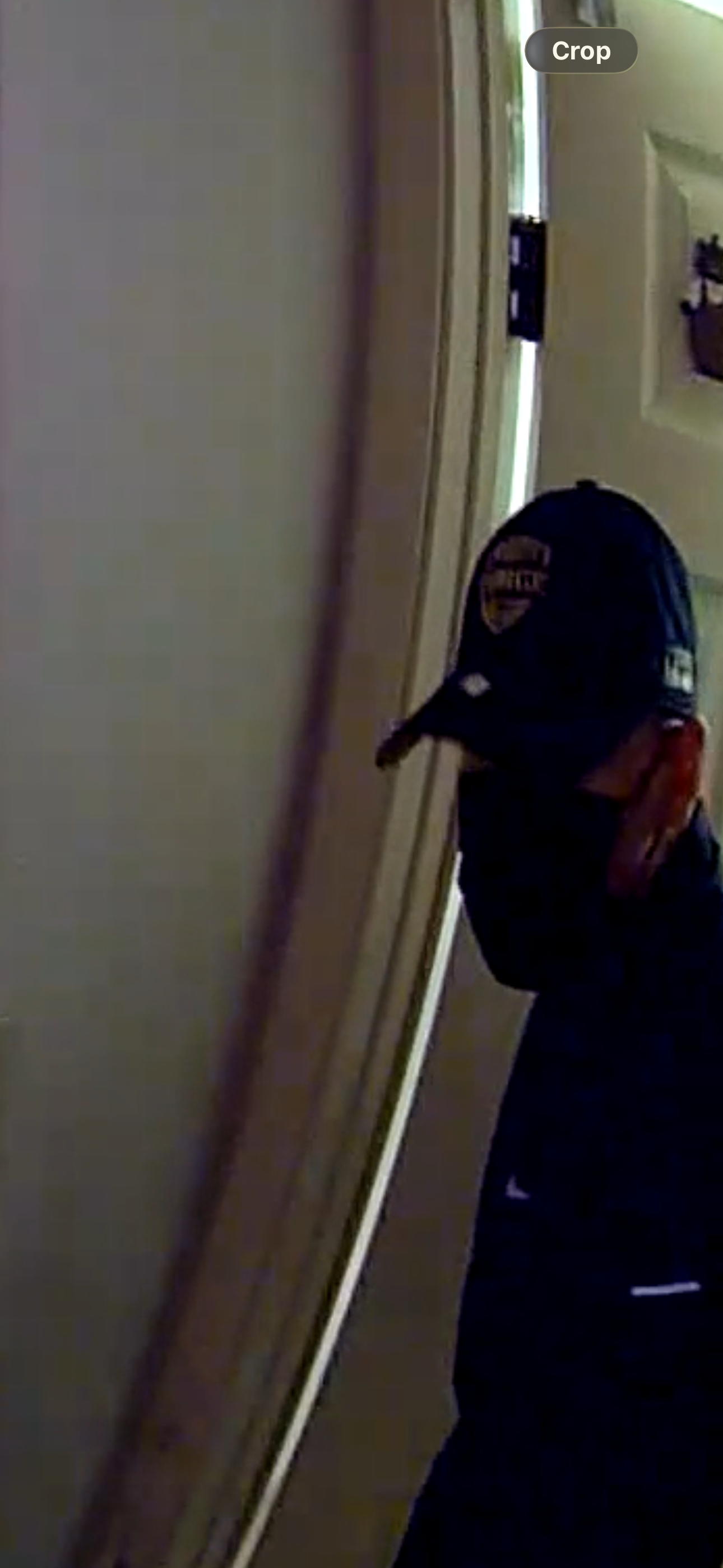 Suspect at bathroom door — dark blue logo cap
